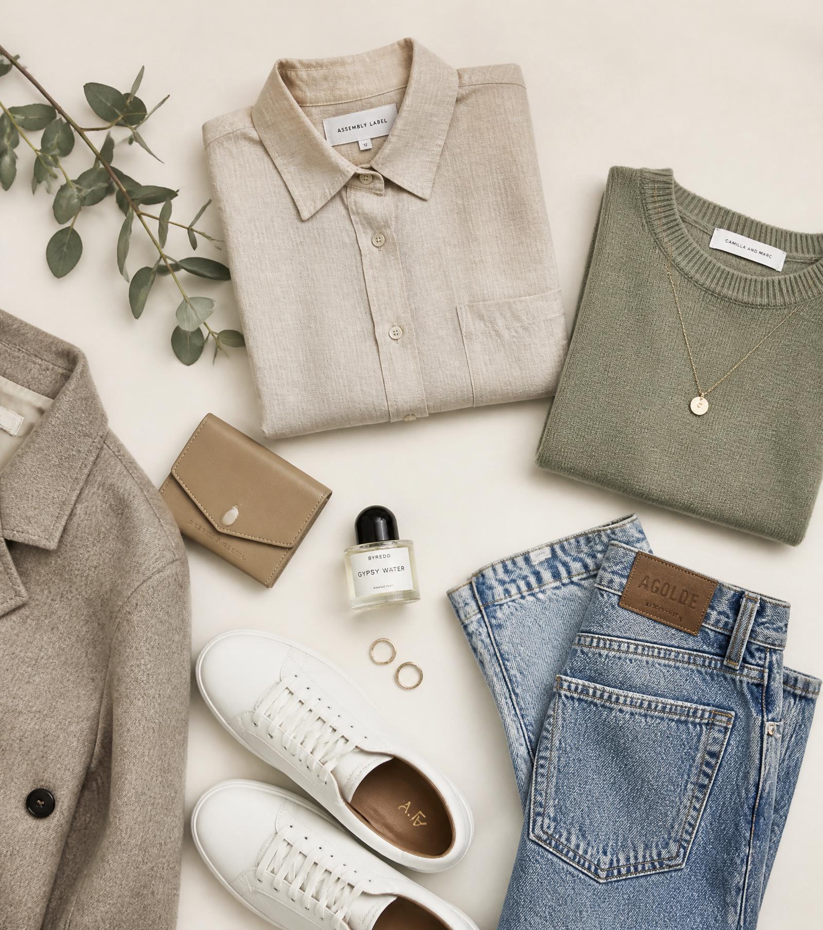 A curated flat lay of a minimalist wardrobe: linen shirt, sage sweater, denim, sneakers